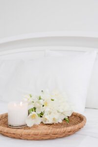 A wooden tray with white flowers and a candle