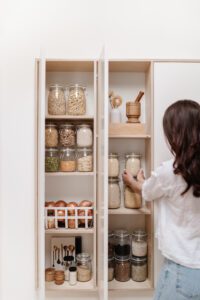 A woman putting a jar back into an organized small pantry