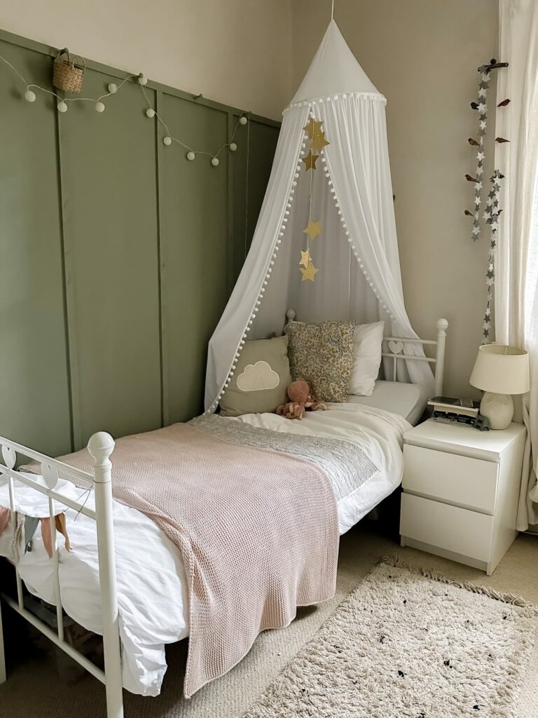 A tween girls bedroom with sage green panelled walls and white bed - walls are Farrow and Ball Lichen