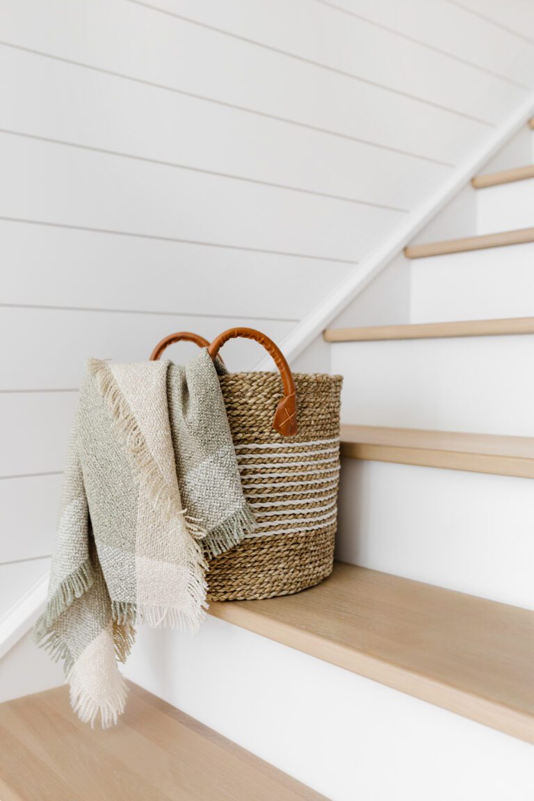 A seagrass basket with blanket, on some stairs