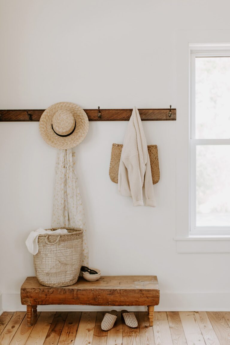 A coat rack with a hat and cardigan hanging on it, in neutral colours