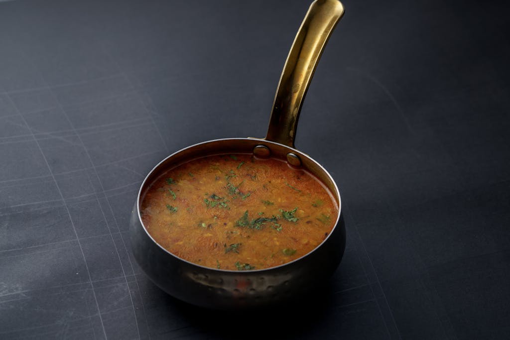 A close-up shot of Indian dal garnished with herbs in a copper pot, offering a taste of traditional cuisine.