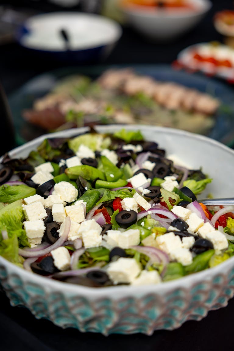 Colorful Greek salad with feta, olives, lettuce, and onions in a ceramic bowl.