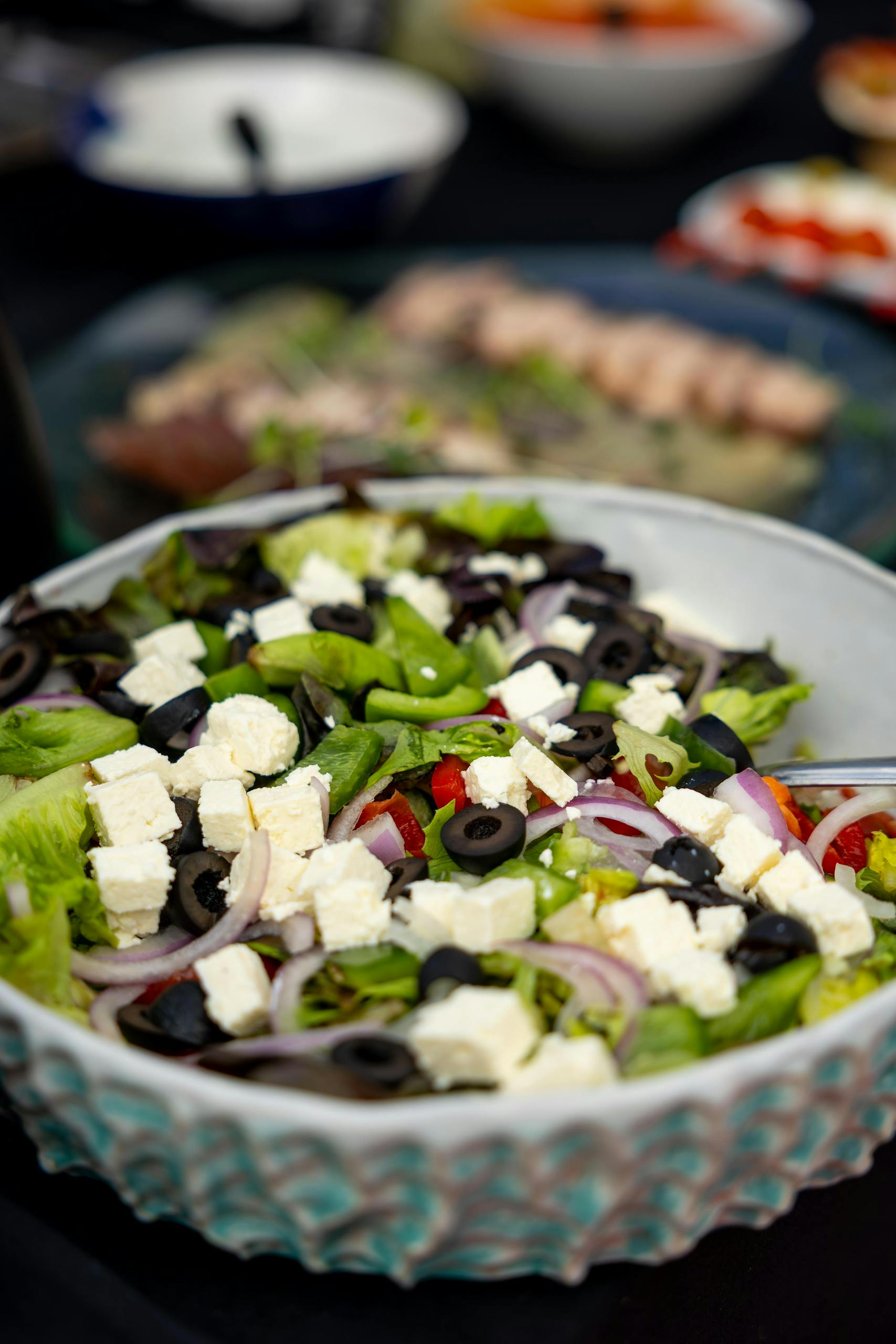 Colorful Greek salad with feta, olives, lettuce, and onions in a ceramic bowl.