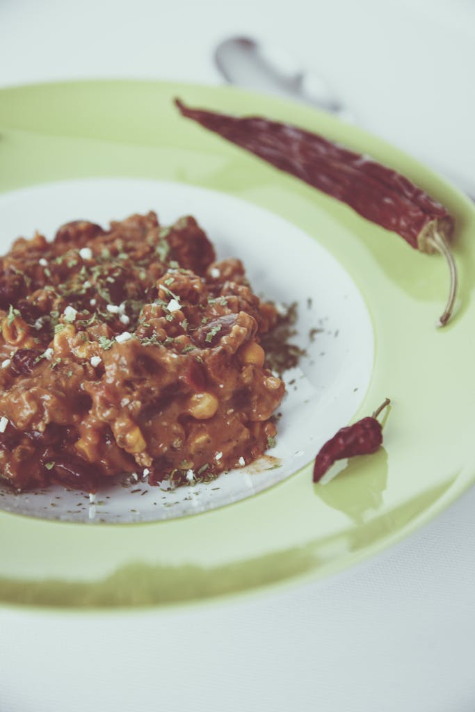 Delicious chili dish served with red chili peppers garnished on a green plate.