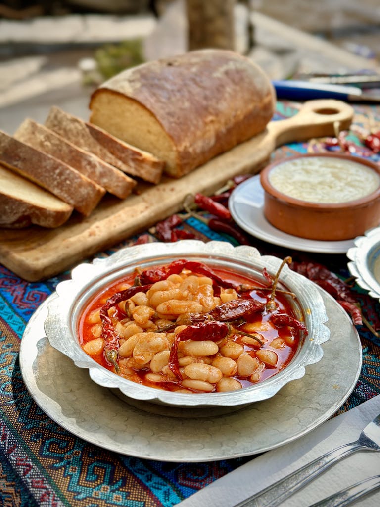 Delicious rustic meal featuring sliced bread and spicy bean dish on a vibrant tablecloth.