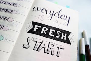 Notebook page featuring motivational quote 'Everyday is a fresh start' with colorful pens.