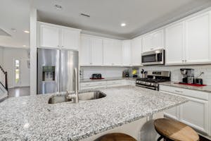 Spacious kitchen featuring granite countertops, white cabinets, and stainless steel appliances.