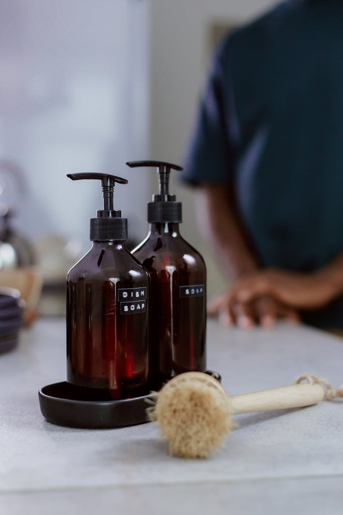 Stylish dish soap bottles with a scrub brush on a kitchen counter, emphasizing cleanliness and elegance.