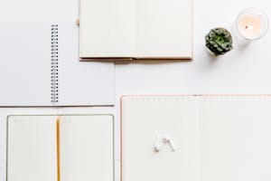 A clean flat lay of notebooks, planners, Airpods, and succulents, ideal for productivity themes.