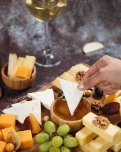 Assorted gourmet cheese platter with honey and white wine pairing.