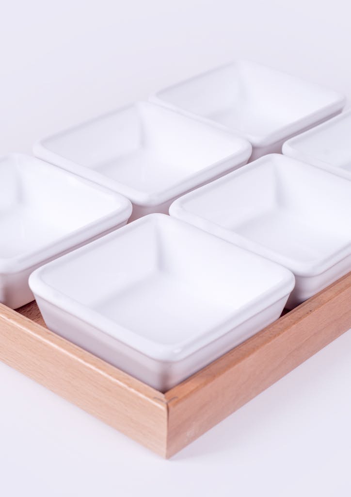 Elegantly arranged white porcelain bowls on a wooden tray for modern dining.