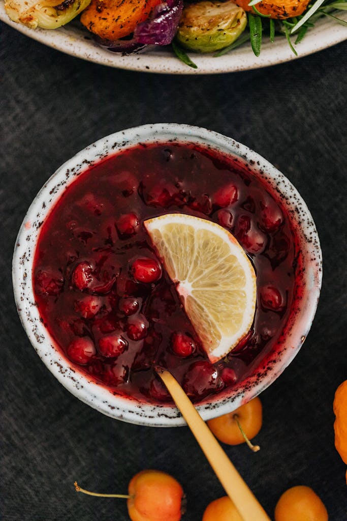 Top view of a bowl of cranberry sauce garnished with a lemon slice.