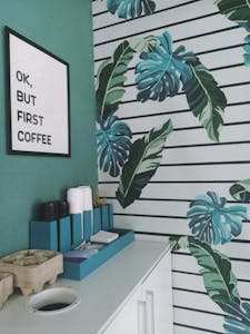Trendy coffee station with tropical wallpaper and motivational text.