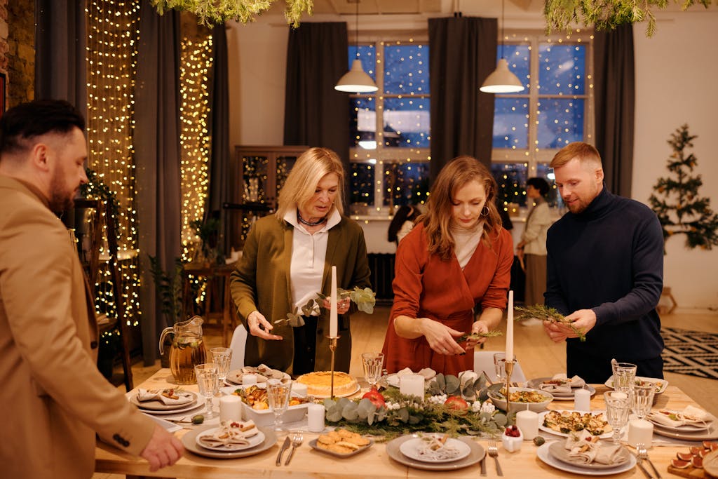 Family setting a festive table for Christmas dinner in a cozy, decorated home.