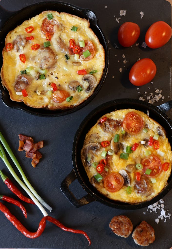 Gourmet omelettes with fresh veggies in cast iron skillets, perfect for brunch.