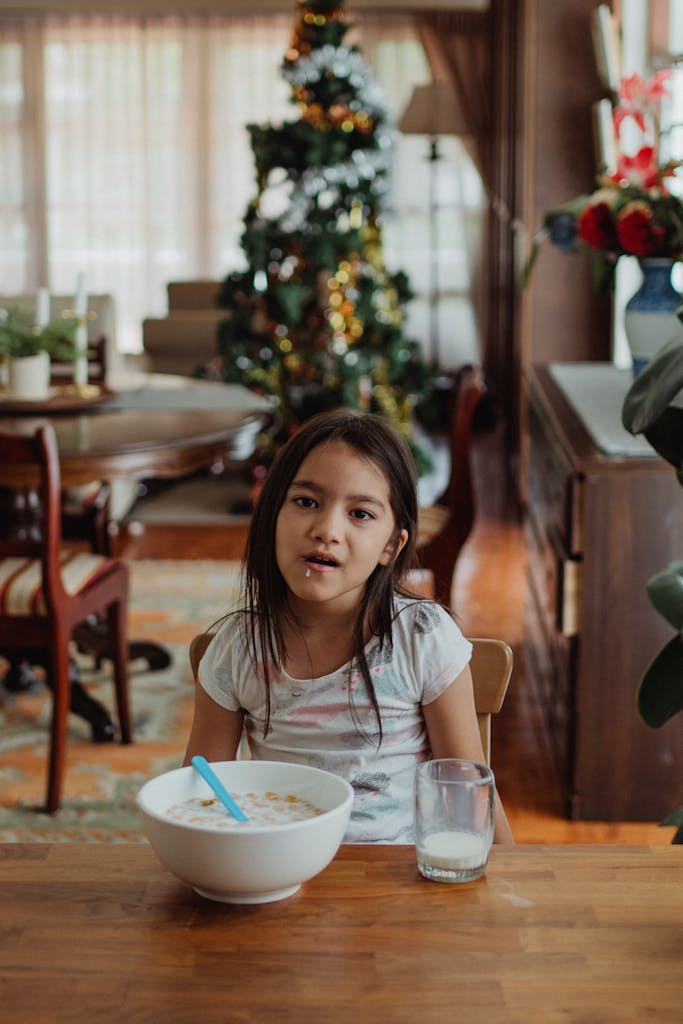 Young girl having breakfast in a cozy dining room with festive Christmas decorations.